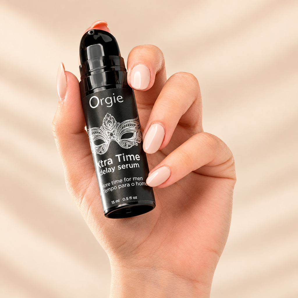 Flacon pompe Orgie Xtra Time delay serum tenu en main, sur fond crème